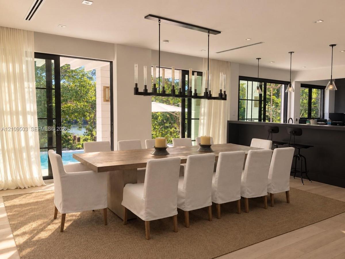 Dining area featuring large-format sliding glass doors, a linear wrought iron chandelier, recessed lighting, wood-finish flooring, and a built-in kitc