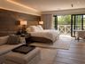 Wood-plank feature wall with recessed accent lighting, wood-finish flooring, and black-framed multi-panel glass doors leading to an exterior balcony