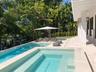 Custom-built swimming pool with integrated spa and stone-paved deck, sheltered by a covered patio with square columns and wall-mounted exterior light 
