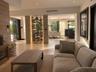 Built-in glass-enclosed wine display with integrated accent lighting, wood-finish flooring, stone-clad feature wall, and recessed ceiling lighting
