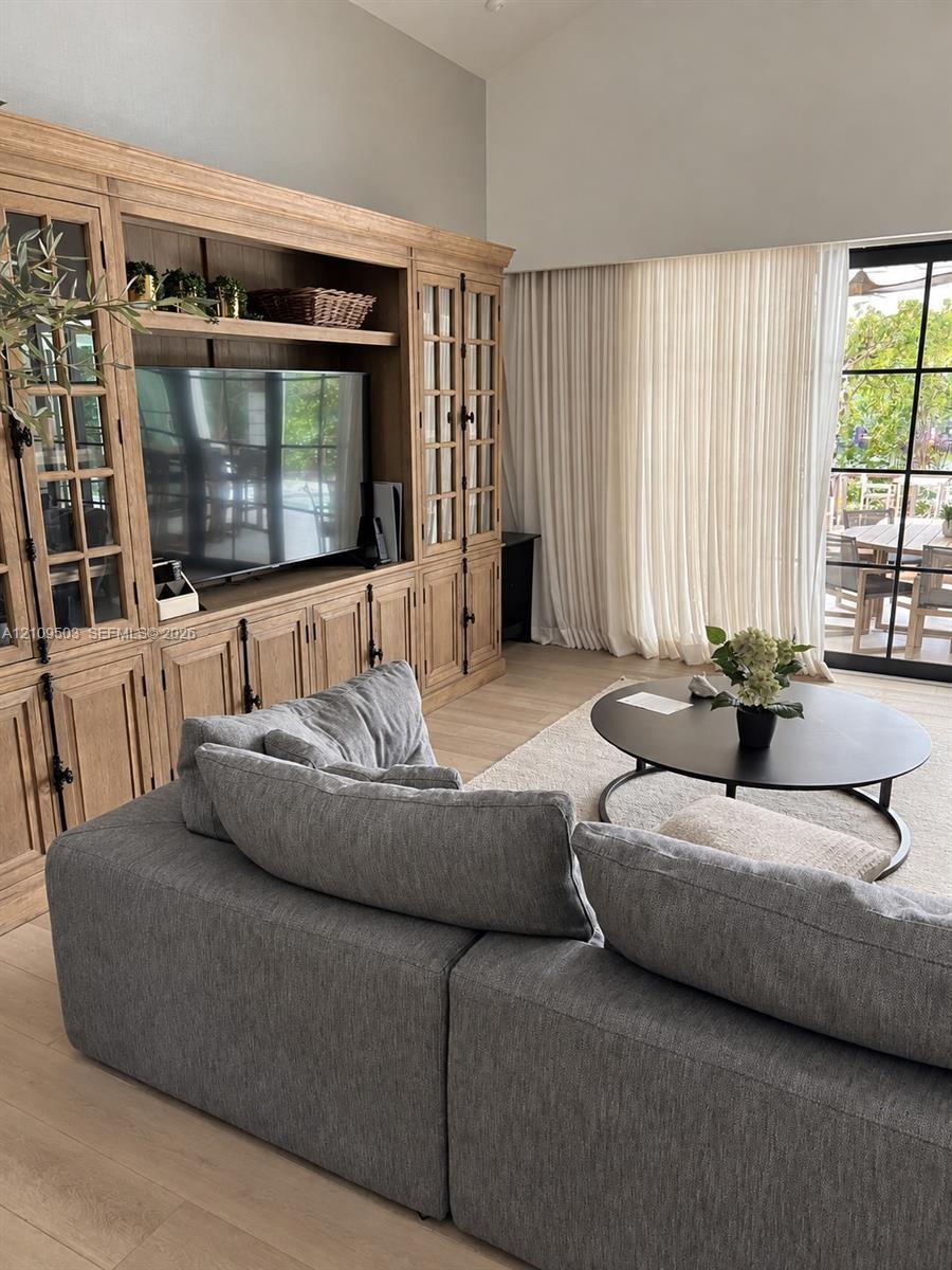 Built-in floor-to-ceiling wood cabinetry with glass-paneled doors, wood-finish flooring, vaulted ceilings, and multi-panel metal-framed glass doors