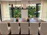 Linear wrought iron chandelier with exposed filament bulbs, floor-to-ceiling metal-framed glass doors, and direct outdoor access