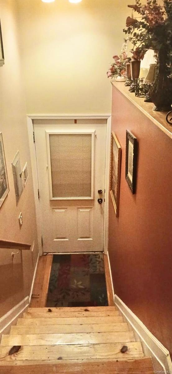 Interior staircase with wooden treads and a handrail, featuring a white door with an integrated window panel
