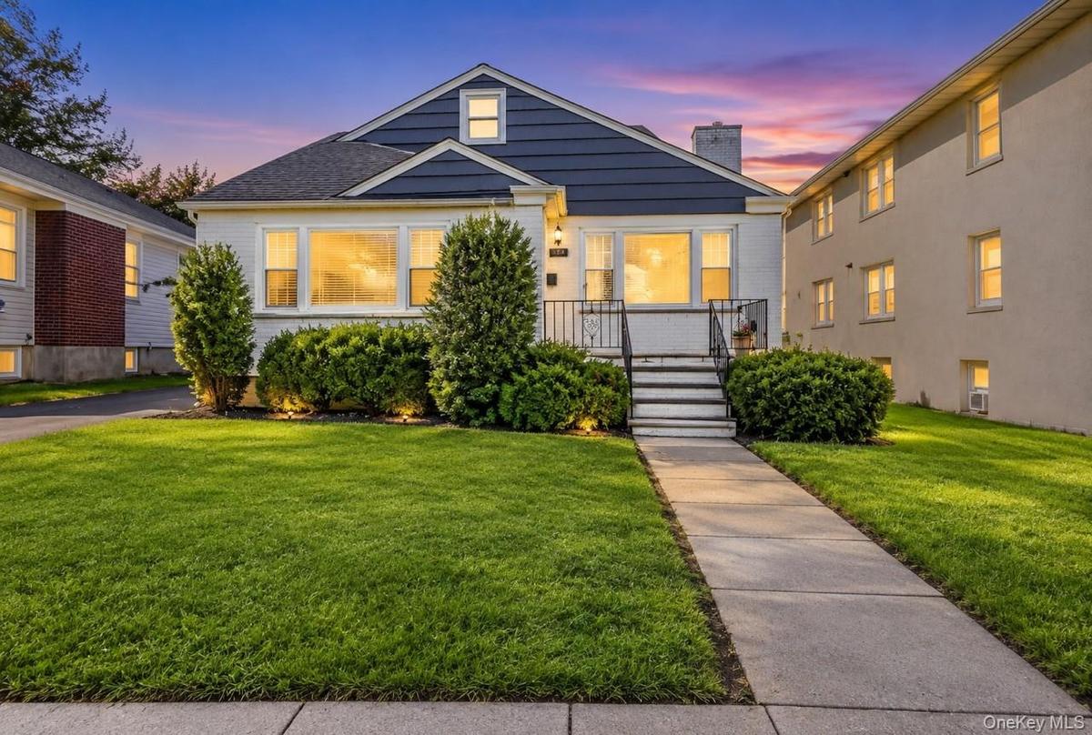 Front exterior featuring a gabled roof, white siding, and dark blue shingle accents