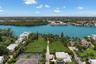 Waterfront parcel featuring extensive lawn, established palm trees, and a hard-surfaced tennis court