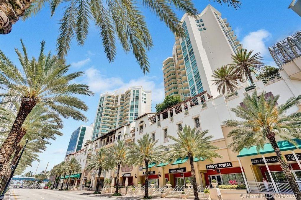 High-rise architectural exterior featuring multi-level balconies, ground-level retail storefronts with canvas awnings, and prominent palm tree landsca