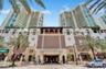 Multi-story high-rise architecture featuring glass balconies, brick-accented exterior masonry, arched entryways, and integrated ground-floor commercia