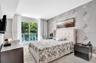 Floor-to-ceiling glass sliding doors opening to a balcony, patterned accent wall covering, and neutral light-toned flooring