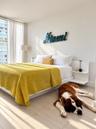 Floor-to-ceiling windows, wood-finish flooring, and built-in bedside shelving units