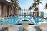 Resort-style swimming pool featuring a central floating lounge island, integrated pool-level sun decks, wood-finish decking, and perimeter cabanas