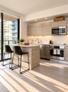 Kitchen featuring horizontal-grain cabinetry, quartz countertops, stainless steel appliances, a center island, and wood-finish flooring