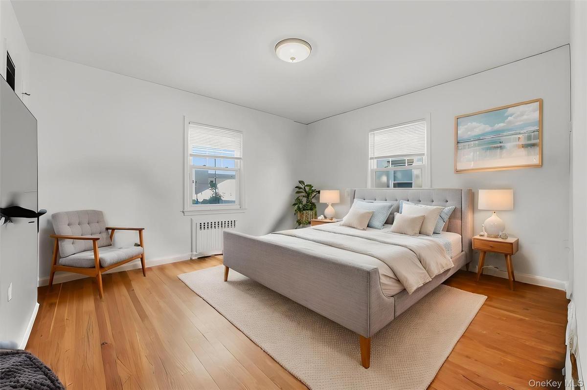 Hardwood flooring throughout, two windows with window treatments, and a ceiling-mounted light fixture