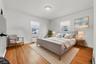 Hardwood flooring throughout, two windows with window treatments, and a ceiling-mounted light fixture