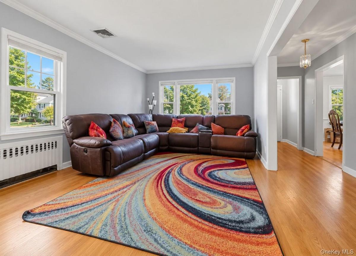 Hardwood flooring throughout, crown molding, double-hung windows, arched entryway, and a hanging light fixture