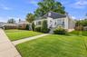 Single-family residence featuring a brick and siding exterior, front porch with metal railings, mature landscaping, and a concrete walkway
