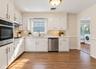 White cabinetry with modern T-bar pulls, stainless steel appliances, and wood-finish flooring