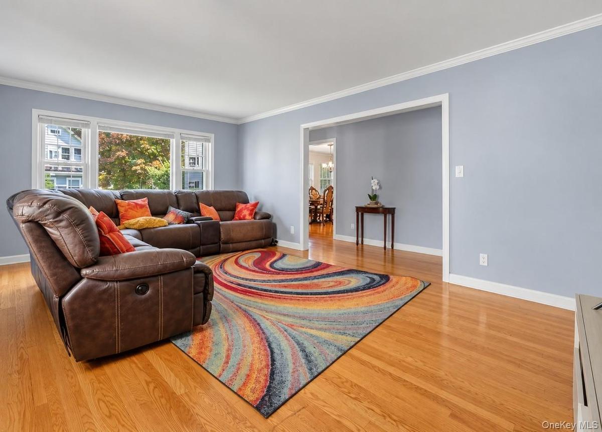 Hardwood flooring, crown molding, wide baseboards, light blue wall paint, and white trim