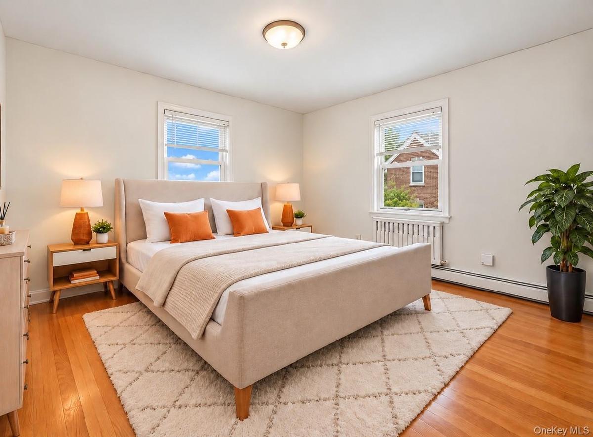 Hardwood flooring, two windows with blinds, and white walls