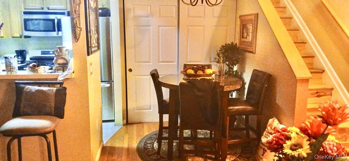 Wood-finish flooring, stainless steel kitchen appliances, dual-panel closet doors, and hardwood staircase with matching handrail