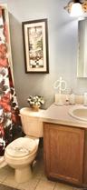 Bathroom featuring a single-sink vanity with wood-finish cabinetry, an integrated basin, a wall-mounted light fixture, and tile flooring