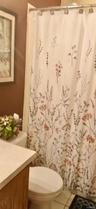 Bathroom featuring a vanity with a countertop, toilet, and a tub enclosure with a shower rod
