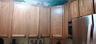 Wood-finish cabinetry featuring raised-panel doors and dark hardware, integrated stainless steel microwave, and stainless steel refrigerator
