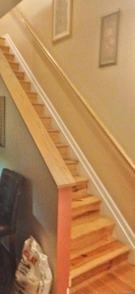 Staircase to second level featuring natural wood-finish treads and a matching wooden handrail
