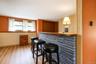 Built-in bar featuring textured dark stone masonry, a wood-finish bar top, vertical wood-paneling accents, and wood-finish flooring