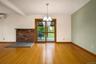 Hard wood flooring, exposed red brick fireplace hearth, sliding glass door to screened porch, multi-light chandelier, and accent wall