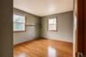 Hard wood flooring, two windows with wood casing, and a built-in wall-mounted shelf