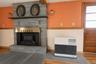 Stone-clad fireplace with a built-in metal firebox, natural stone hearth, kerosine heater, wood-finish flooring, wood-framed multi-pane door, and dual