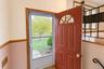 Entryway featuring a solid wood door with a semi-circular glass insert, a storm door, wood-trimmed door casing, decorative chair rail, and a wrought i