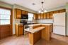 Kitchen featuring wood cabinetry, solid surface countertops, a 2-tiered island with breakfast bar seating, tile flooring, and a glass-paneled exterior