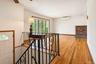 Hard wood flooring, brick fireplace surround, decorative wrought iron railing, expansive picture window, and wall-mounted climate control unit part of