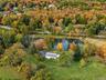 Aerial perspective featuring a detached structure, private pond, and expansive acreage defined by mature deciduous trees