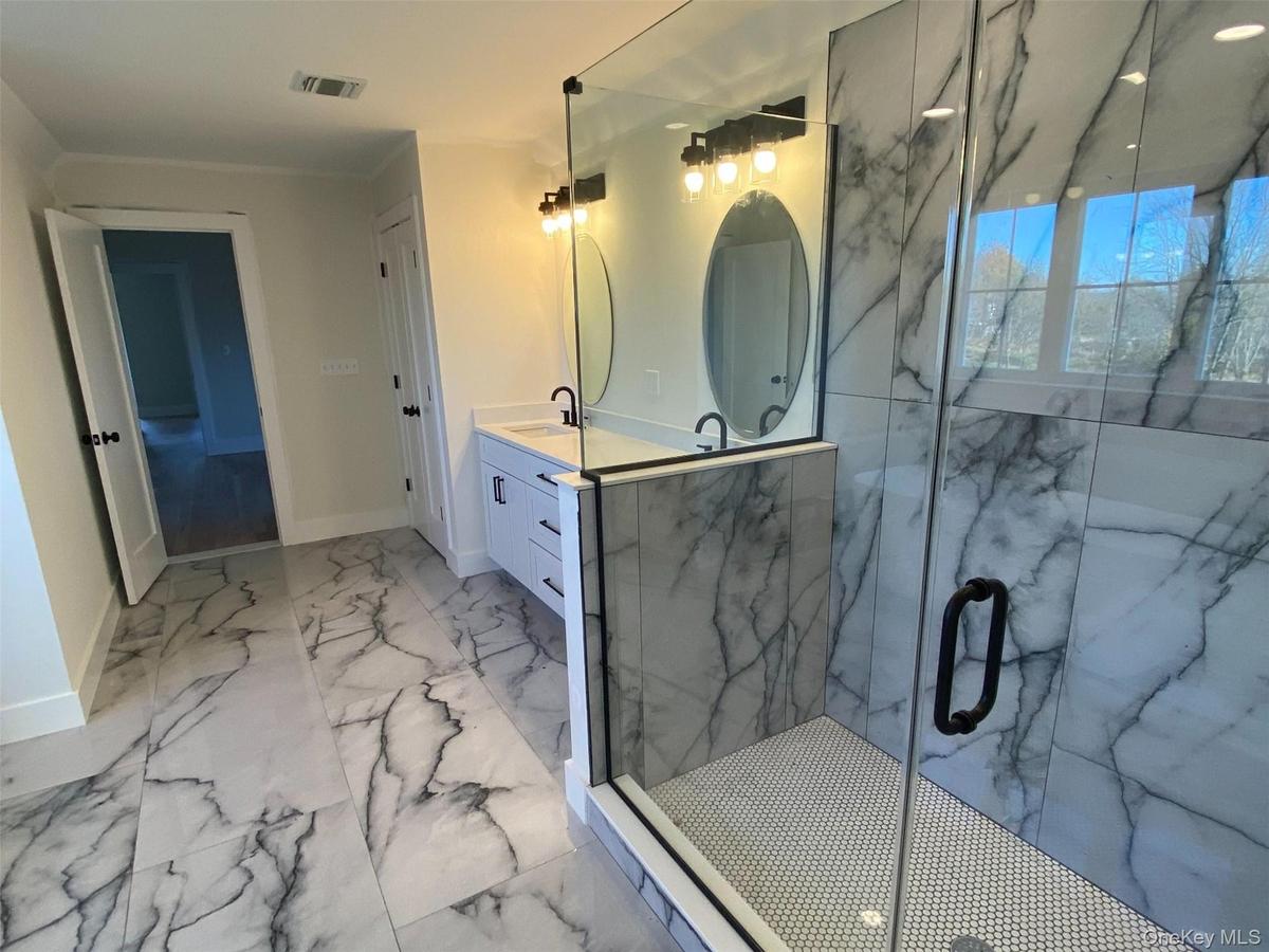 The glass enclosed shower features wall to wall tile.