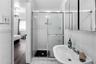Shower enclosure with sliding glass doors, ceramic wall tiling, pedestal sink with chrome faucet, and triple-pane medicine cabinet