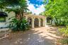 Spanish-style exterior featuring a covered entryway with arched openings, decorative columns, red clay tile roofing, and metal security gates
