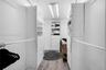 Walk-in closet featuring white built-in shelving, multiple pull-out storage drawers, dual hanging rods, and wood-finish flooring