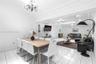 Open-concept living and dining area featuring large-format tile flooring, crown molding, chair rail detailing, recessed lighting, and a decorative cry