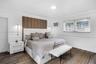 Bedroom featuring crown molding, chair rail trim, wood-finish flooring, a vertical wood-panel accent wall, and wall-mounted gold-toned light fixtures