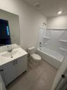 Bathroom featuring a vanity with a solid-surface countertop, an integrated sink, a full-height wall mirror, a ceramic tile floor, and a tub-shower com