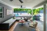 Covered patio featuring tiled flooring, two ceiling fans, and structural support columns, opening to a swimming pool and perimeter fencing