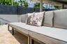 Outdoor patio featuring natural stone pavers, a covered lanai with structural columns, and a perimeter privacy fence