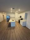 Kitchen featuring white cabinetry, solid-surface countertops, center island with an integrated stainless-steel sink, stainless-steel appliances, and w