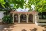 Stucco exterior featuring a decorative arched portico with classical-style columns, ornate iron gated entryways, a terracotta-style tile roof, and a c