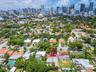 Aerial perspective of residential property featuring a flat roof with solar panel installation, mature landscaping, and an expansive cityscape backdro