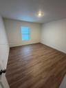 Wood-finish flooring, neutral wall tones, recessed ceiling lighting, and a window featuring adjustable horizontal blinds
