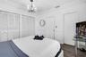 Room featuring wood-finish flooring, floor-to-ceiling louvered-door closets, crown molding, chair rail trim, and a multi-arm chandelier with a decorat
