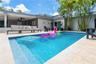 In-ground swimming pool with tile surround, covered patio with recessed ceiling fans, and natural stone-finish decking
